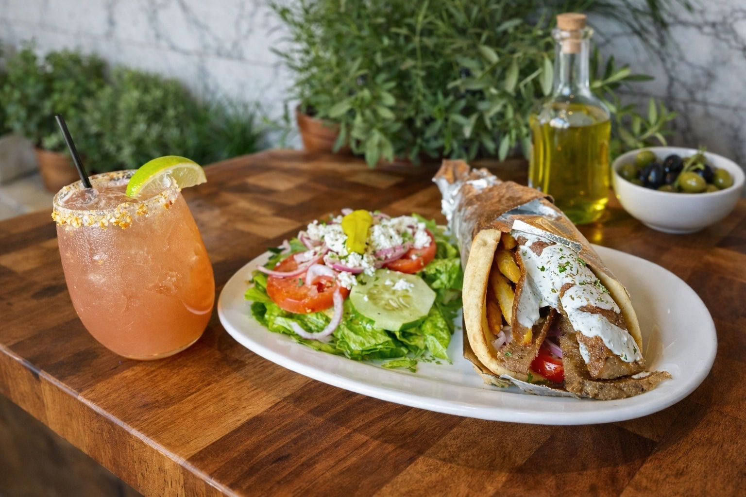A gyro and cocktail on a wooden table at Yamas